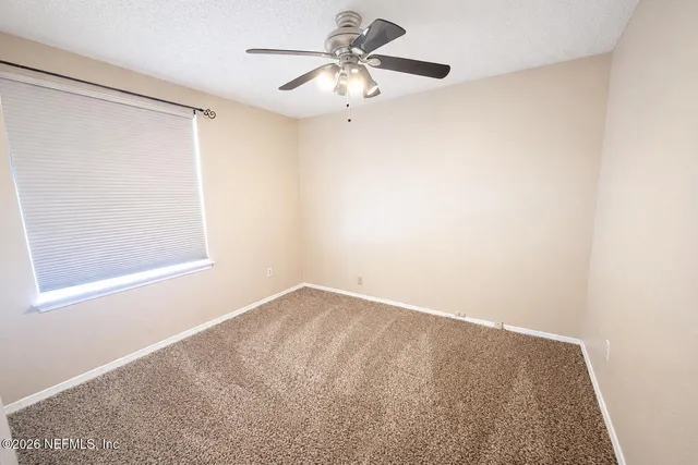 an empty room with a window and a fan
