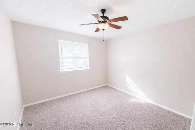 an empty room with a window and a fan