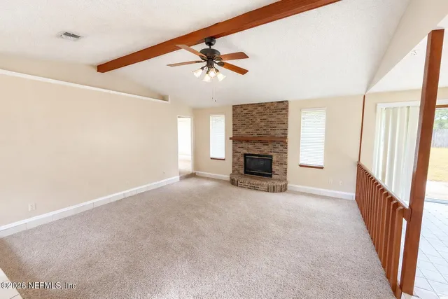 an empty room with windows and fireplace