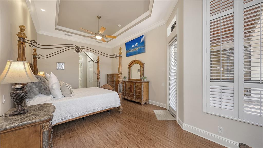 6919 Dominion Lane Lakewood Ranch, FL 34202 - Photo 34 of 99 a bedroom with a bed ceiling fan and a wooden floor