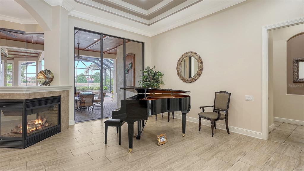 6919 Dominion Lane Lakewood Ranch, FL 34202 - Photo 9 of 99 a living room with furniture a fireplace and a floor to ceiling window