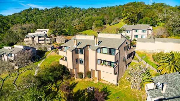 an aerial view of a residential apartment building with a yard and parking spaces
