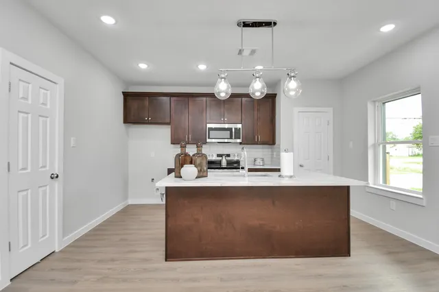 a large kitchen with stainless steel appliances granite countertop a sink a stove and a refrigerator