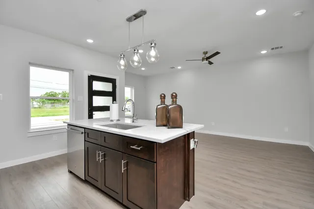 a kitchen with a sink chandelier and wooden floor