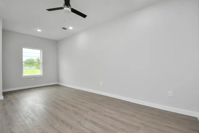an empty room with wooden floor and windows