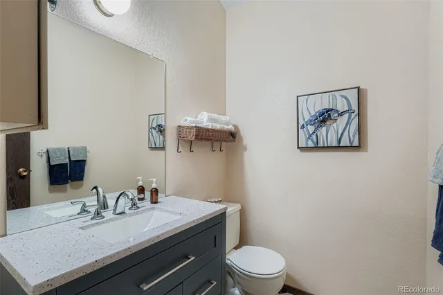a bathroom with a granite countertop sink mirror vanity and toilet