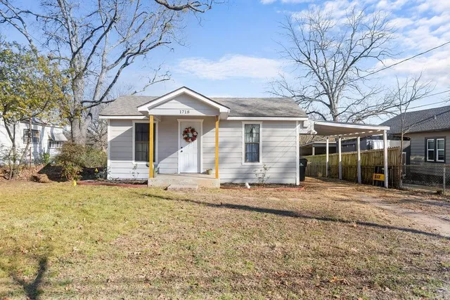 a front view of a house with a dirt yard and a large tree