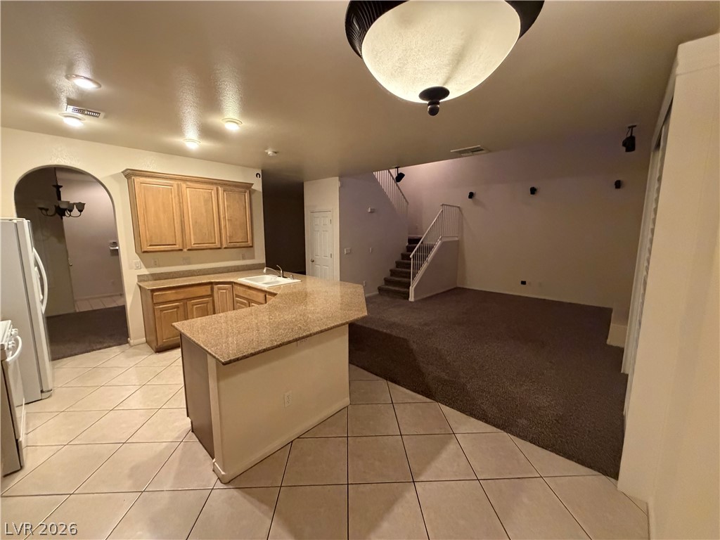 7629 Rory Court Las Vegas, NV 89129 - Photo 5 of 25 A functional kitchen with granite counters opens to a comfortable living space with a staircase.