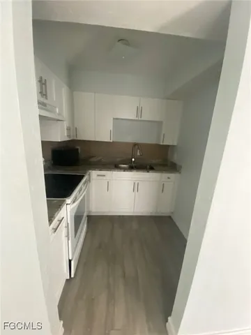 a kitchen with granite countertop a sink a stove and cabinets