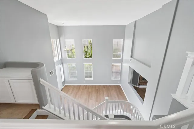 a view of a hallway to a livingroom with wooden floor and stairs