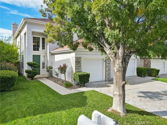 a view of a white house with a yard and a large tree