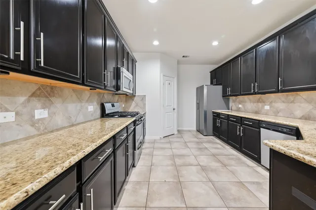 a kitchen with granite countertop a sink a counter top space and cabinets