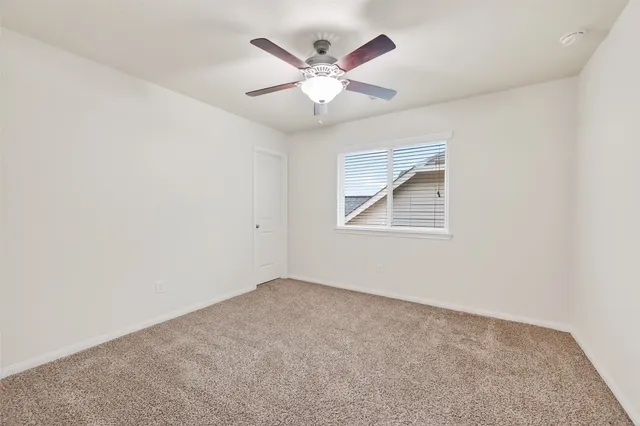 an empty room with window and ceiling fan