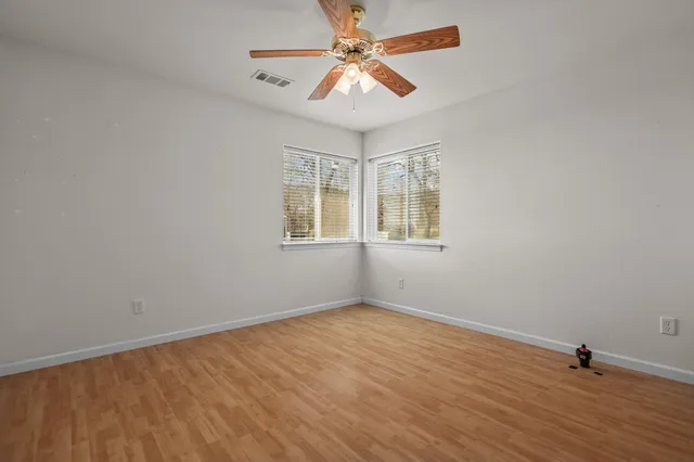 a view of empty room with wooden floor and fan