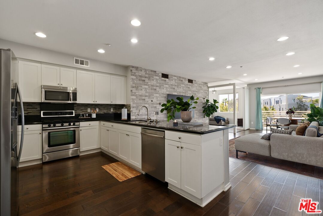 a kitchen with stainless steel appliances a stove a sink a center island and furniture