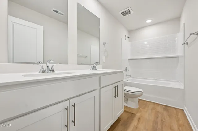 a bathroom with a double vanity sink a toilet and a bathtub