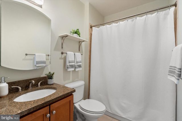 a bathroom with a granite countertop sink toilet and a mirror