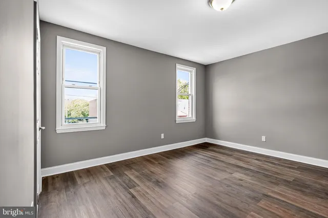 a view of an empty room with window and wooden floor