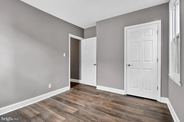 a view of an empty room with wooden floor and closet
