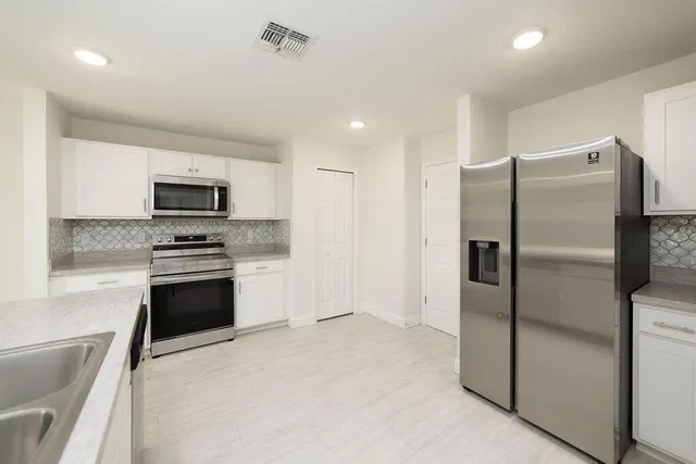 a kitchen with granite countertop a refrigerator and a stove top oven