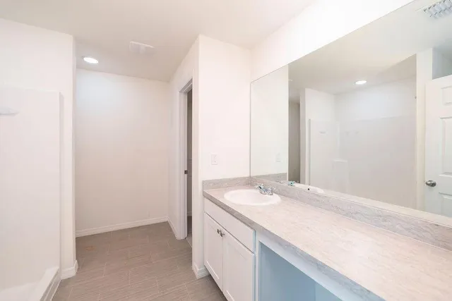 a bathroom with a granite countertop sink a mirror and a shower