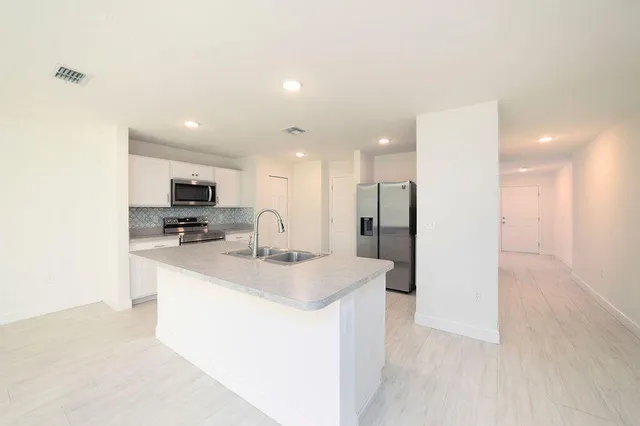 a kitchen with stainless steel appliances kitchen island sink refrigerator and microwave