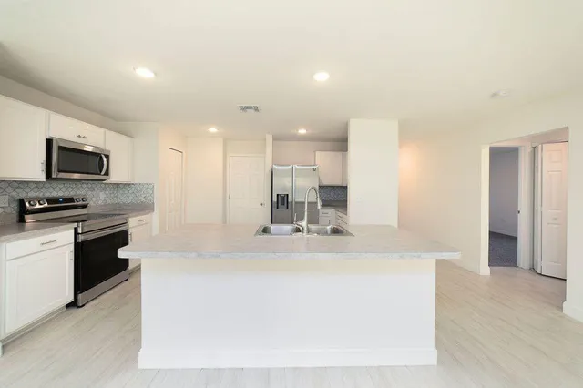 a large kitchen with kitchen island a sink stainless steel appliances and cabinets