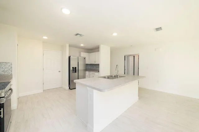 a large white kitchen with a sink and refrigerator