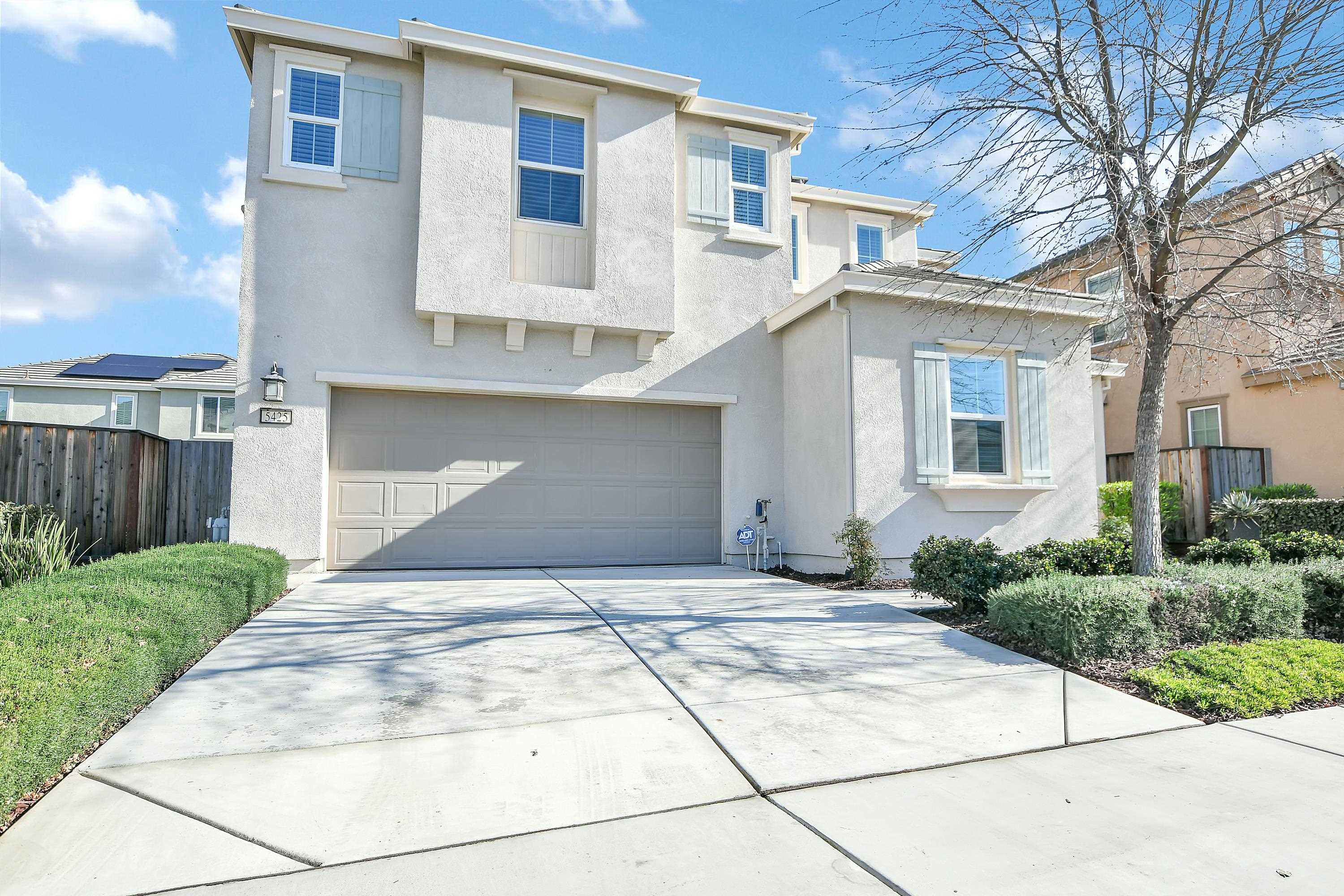 Traditional home with stucco siding, driveway, and an attached garage