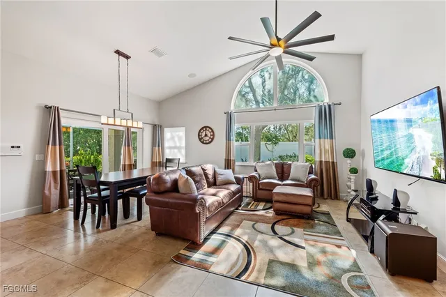 a living room with furniture a ceiling fan and a large window