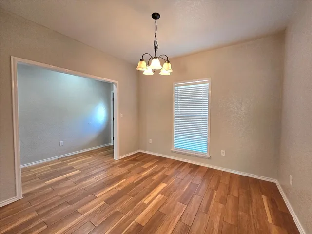 a view of a room with wooden floor chandelier and a window