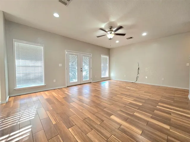 a view of an empty room with window and wooden floor