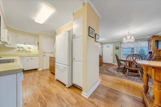 a kitchen with stainless steel appliances a stove a refrigerator a dining table and chairs with wooden floor