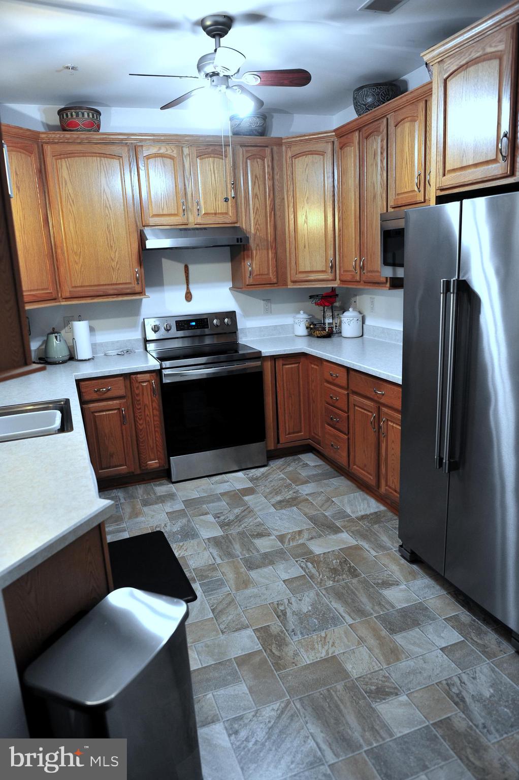 4000 Village Way, Unit 202 Boothwyn, PA 19061 - Photo 4 of 15 a kitchen with stainless steel appliances granite countertop a stove a sink dishwasher and a refrigerator with wooden cabinets