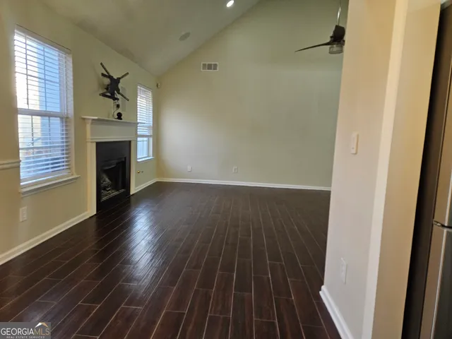 an empty room with wooden floor fan and windows