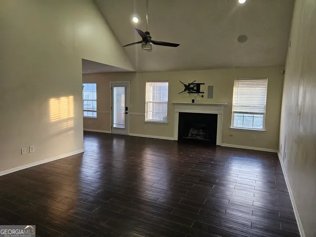 a view of an empty room with wooden floor fireplace and a window