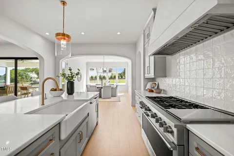 a dining room with wooden floor a chandelier a wooden table and chairs
