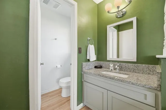 a bathroom with a granite countertop sink toilet and mirror