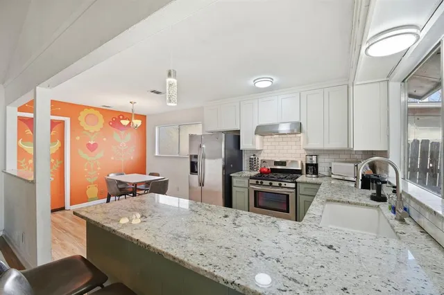 a kitchen with granite countertop a sink stove and refrigerator