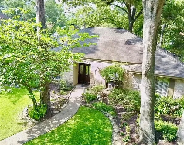 a backyard of a house with plants and large tree