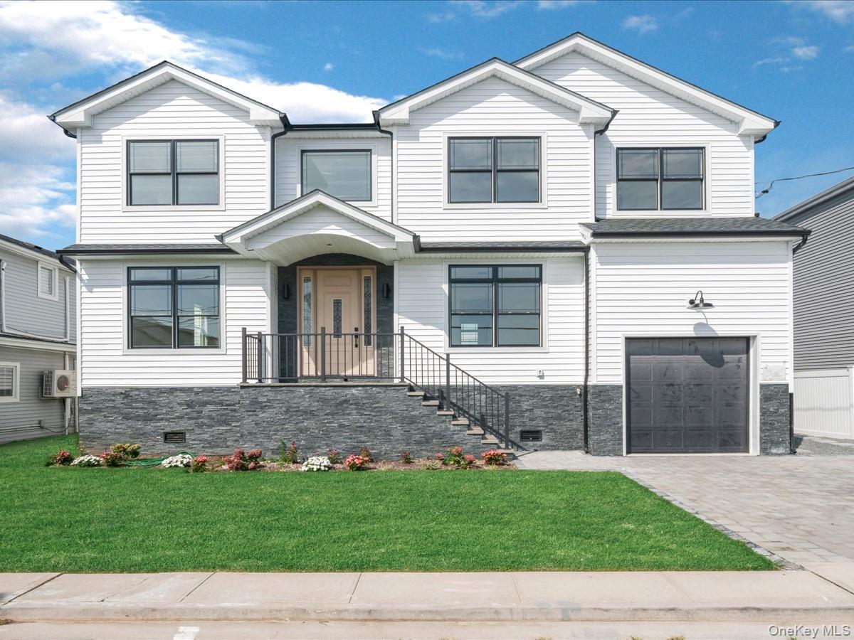 White siding exterior featuring a multi-gable roofline, black-framed windows, a light wood-finish entry door, and dark stone-clad foundation