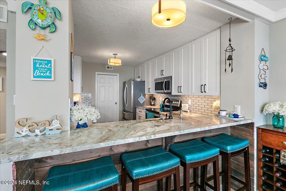 1301 1st Street South, Unit 1505 Jacksonville Beach, FL 32250 - Photo 12 of 36 a kitchen with granite countertop a table chairs stove and microwave