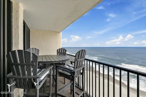 a balcony with wooden floor table and chairs