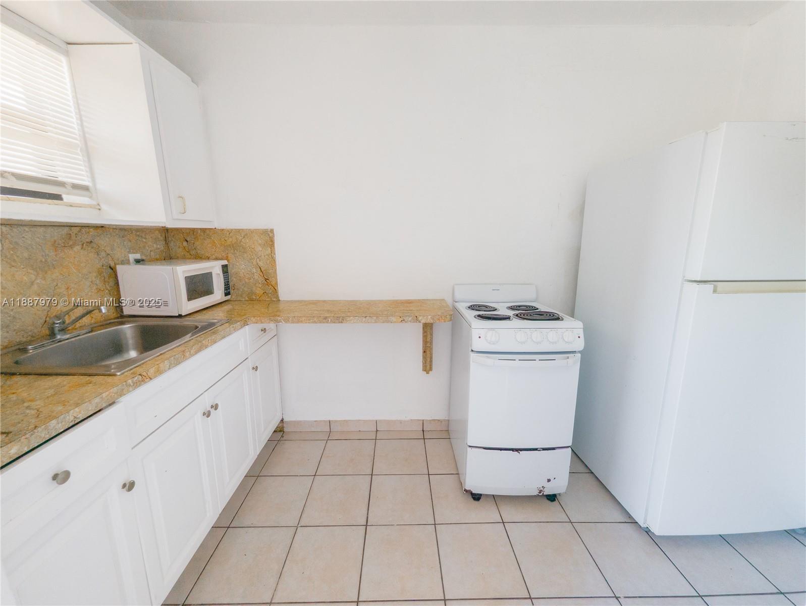 1736 Northwest 19th Street, Unit 5 Miami, FL 33125 - Photo 3 of 9 a kitchen with a sink a stove and cabinets