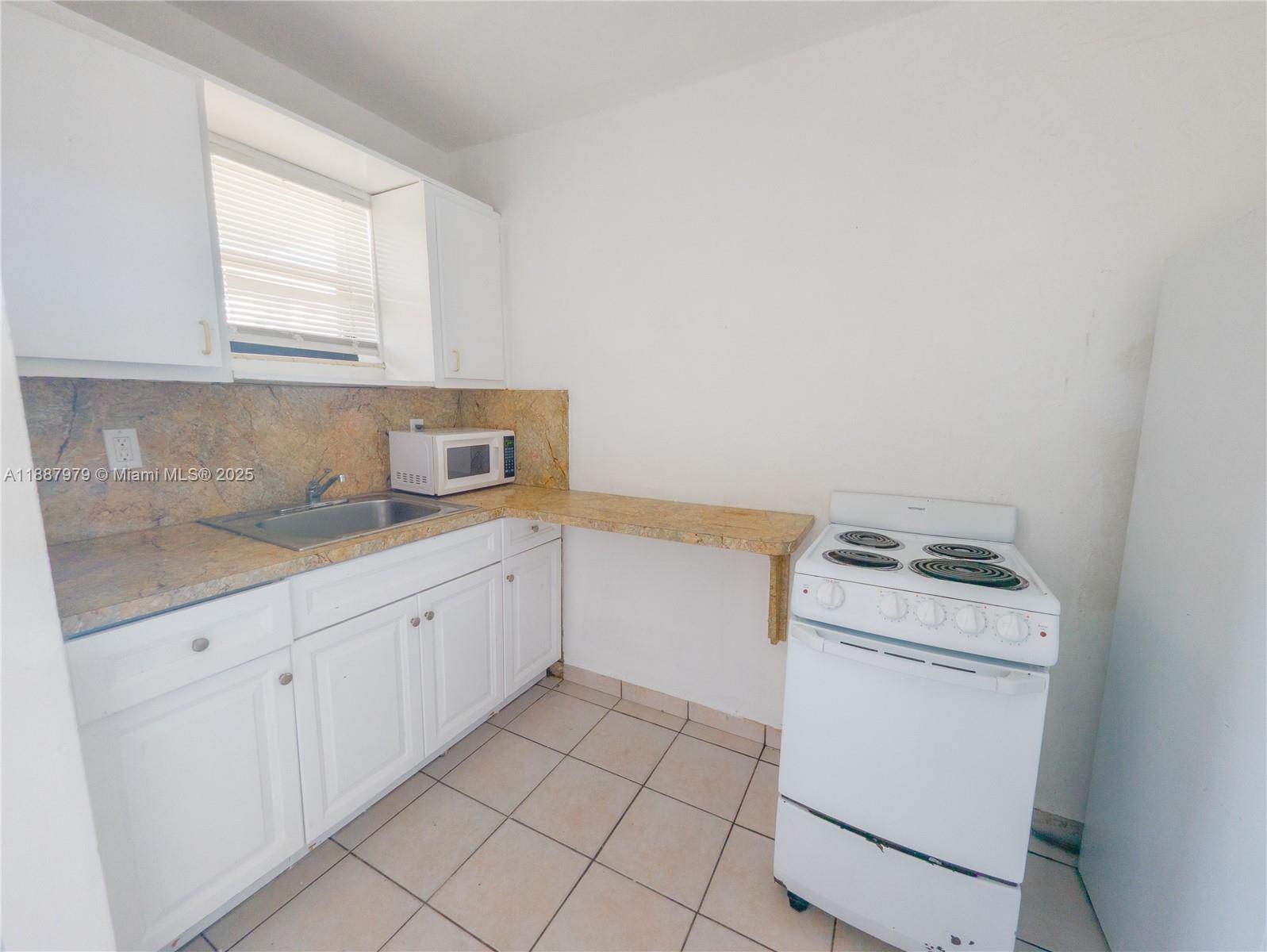1736 Northwest 19th Street, Unit 5 Miami, FL 33125 - Photo 4 of 9 a kitchen with a stove top oven sink and cabinets