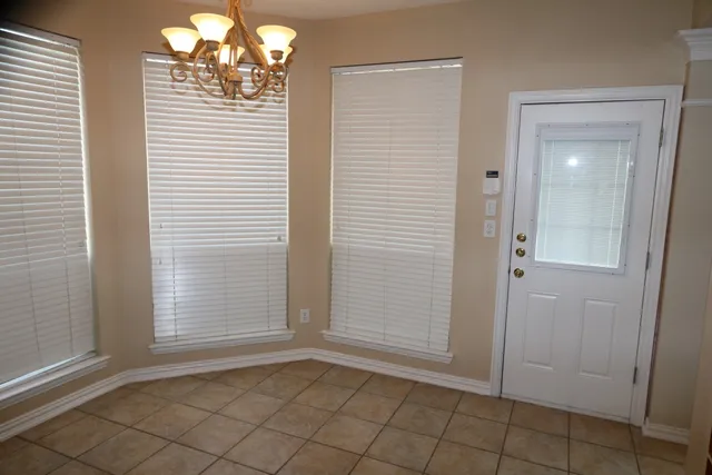 a view of an empty room with window and chandelier fan