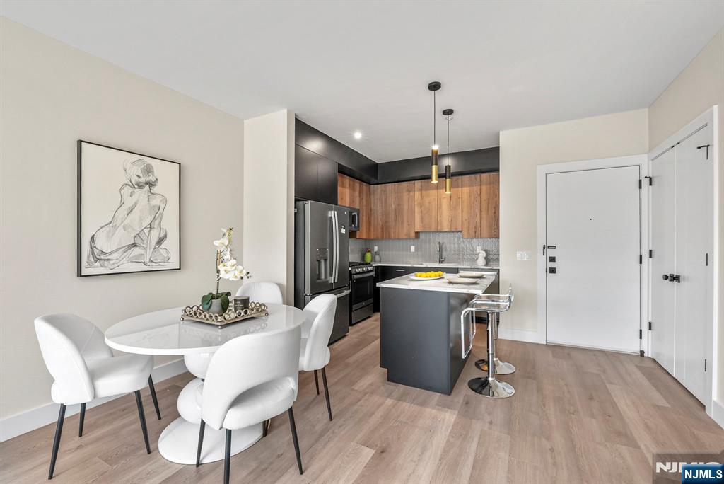 2021 Jones Road, Unit 102 Fort Lee, NJ 07024 - Photo 4 of 11 a kitchen with a dining table chairs refrigerator and cabinets