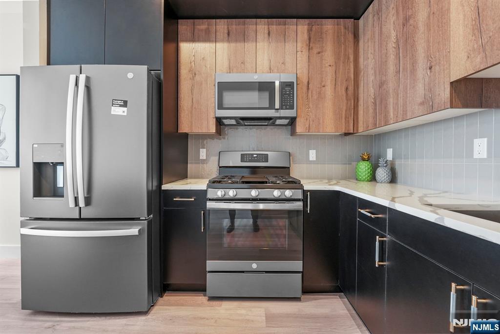2021 Jones Road, Unit 102 Fort Lee, NJ 07024 - Photo 5 of 11 a kitchen with stainless steel appliances granite countertop a refrigerator a stove a sink and a microwave