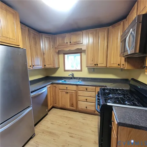 a kitchen with granite countertop stainless steel appliances a stove cabinets and a window