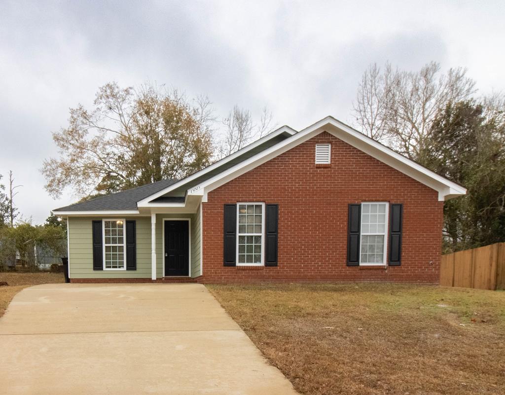 a front view of house with yard and trees in the background